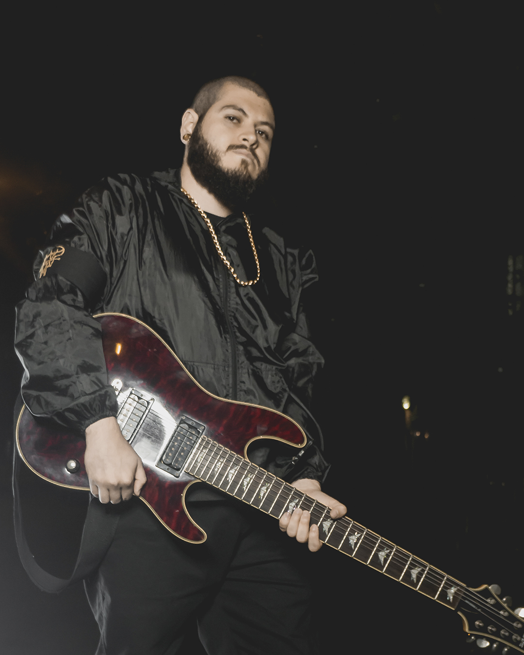 Foto de guitarrista de la banda ground of chaos sostienendo una guitarra en la noche con ropa negra
