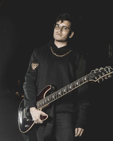Foto de guitarrista de la banda ground of chaos sostienendo una guitarra en la noche con ropa negra